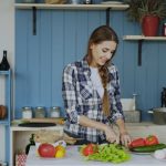 Cheerful young woman cooking breakfast in the kitchen early morning at home