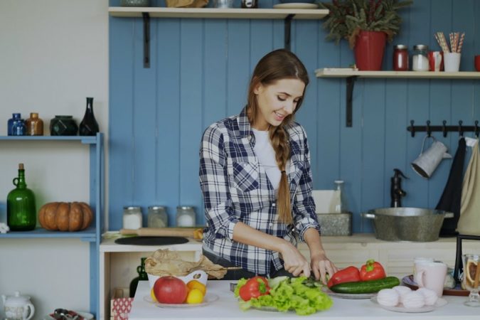 Cheerful young woman cooking breakfast in the kitchen early morning at home