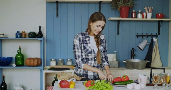 Cheerful young woman cooking breakfast in the kitchen early morning at home