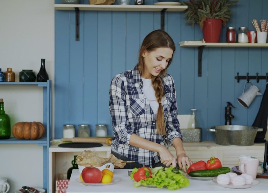 Cheerful young woman cooking breakfast in the kitchen early morning at home